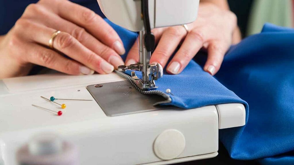 A woman is sewing a piece of fabric on a sewing machine.